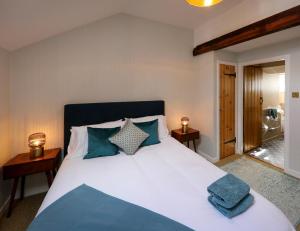 a bedroom with a large bed with blue pillows at Postbox Cottage in Melrose