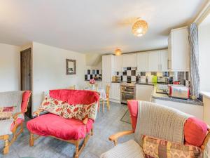 a living room with red chairs and a kitchen at Yew Tree Cottage in Welshpool