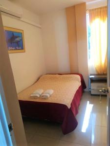 una camera da letto con un letto e due pantofole sopra di Hostal Terito a Puerto Baquerizo Moreno