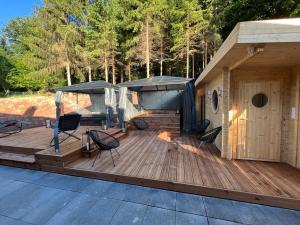 une grande terrasse en bois avec des chaises et une maison dans l'établissement EVASION gîtes et spa, à Saint-Léonard