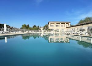 ein großer Wasserkörper mit Stühlen und einem Gebäude in der Unterkunft Appartement 321 avec deux chambres - LES SUITES DE ROBINSON - Résidence avec piscine en bord de Siagne, à Mandelieu-La-Napoule in Mandelieu-la-Napoule