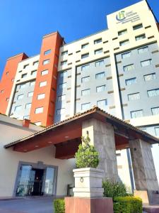 um prédio de hotel com um canteiro de flores em frente a ele em CHN Hotel Monterrey Norte, Trademark Collection by Wyndham em Monterrey