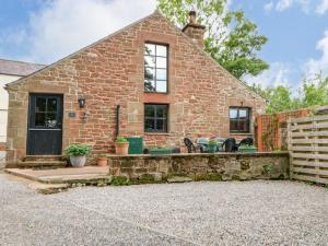 een bakstenen huis met een patio ervoor bij The Old Byre in Sandford