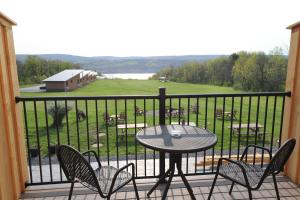 uma varanda com uma mesa e cadeiras e vista para um campo em Lakeside Resort em Watkins Glen