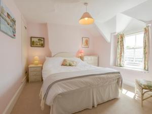 a bedroom with a white bed and a window at Agar Cottage in Port Isaac