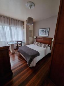 a bedroom with a large bed and wooden floors at Piso de 3 habitaciones a 3 minutos de la playa. in Ribeira