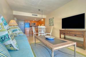 a living room with a blue couch and a flat screen tv at Sugar Sands B in St. Pete Beach