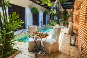 a patio with a table and chairs and a swimming pool at Hotel Capellán de Getsemaní in Cartagena de Indias