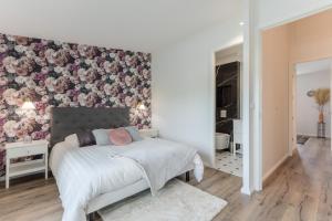 Un dormitorio con una cama con una pared de acento floral en Echoppe typique de Bordeaux rénovée 3 ch./3 sdb, en Talence