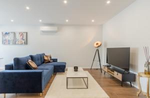 uma sala de estar com um sofá azul e uma televisão em Echoppe typique de Bordeaux rénovée 3 ch./3 sdb em Talence