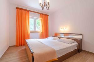 a bedroom with a bed and a window with orange curtains at Holiday home in Blato Insel Korcula 6411 in Prigradica