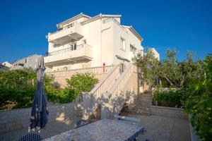 a white building with a table and an umbrella at Rooms & Studio Villa Fio in Hvar