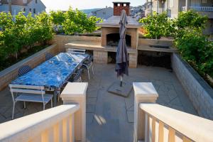a patio with a table and a grill with an umbrella at Villa Fio - Rooms & Studio in Hvar