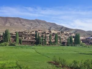 a village in a field with mountains in the background at Auberge restaurant Afoud in Agoudal