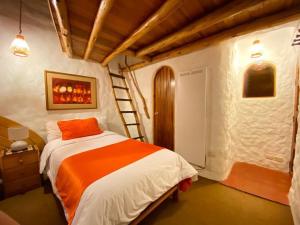 Un dormitorio con una cama con una almohada naranja y una escalera en Hostal Madre Tierra, en Cusco