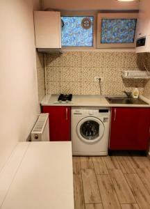 a small kitchen with a washing machine and red cabinets at Grozavesti Apartment near University in Bucharest