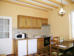 a kitchen with wooden cabinets and a table and a microwave at Gîte Aurouer, 3 pièces, 4 personnes - FR-1-489-258 in Aurouer