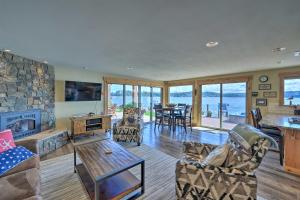 a living room with a stone fireplace and a table at Similk Bay Retreat with Deck, Fire Pit and Hot Tub! in Anacortes