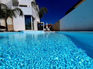 una piscina de agua azul frente a una casa en La Perla di Marzamemi en Marzamemi