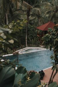 a swimming pool with a gazebo and trees at Kusfarm Bali in Selemadeg
