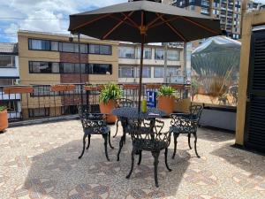 a table and chairs with an umbrella on a patio at Hotel L&L Mansión in Bogotá