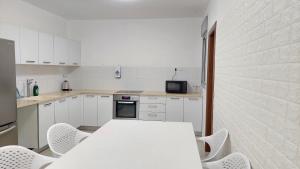 アシュケロンにあるAshkelon City center Apartmentの白いキッチン(白いテーブルと椅子付)