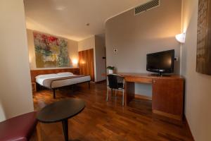 a room with a bed and a desk with a television at HOTEL QUERINI Budget & Business Hotel Sandrigo in Sandrigo