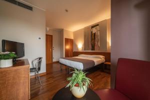 una camera d'albergo con un letto e una TV di HOTEL QUERINI Business Hotel Sandrigo a Sandrigo