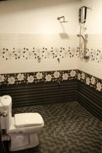 a bathroom with a toilet and flowers on the wall at Sigiri Anu Homestay in Sigiriya