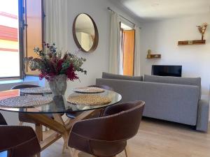 uma sala de estar com uma mesa de vidro e um sofá em Hispalis Jardines de Murillo em Sevilha