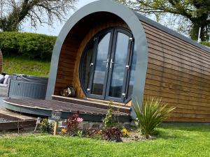 a small house with a large window and a bench at Great House Farm Luxury Pods and Self Catering in Crickadarn