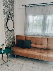 Sofá marrón en la sala de estar con ventana en Studio Ocean, en Paralia Dionisiou