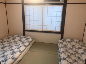 two beds in a room with a window at WUMETEI Japanese-style lodge in Kyoto