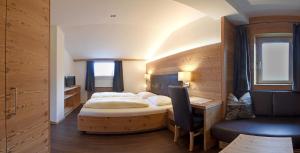 a bedroom with a bed and a desk and a chair at Hotel Garni Vanadis in Ortisei