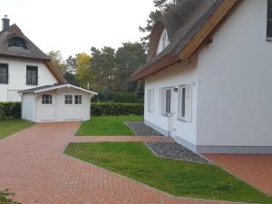 a white house with a brick driveway at Weißes Traumhaus in Glowe