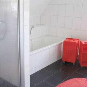 a bathroom with a white tub and a red stool at Weißes Traumhaus in Glowe +10 photos