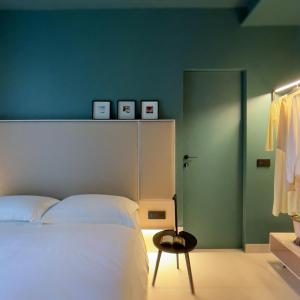 una camera con un letto bianco e una parete verde di Le stanze di Caterina a Cesenatico