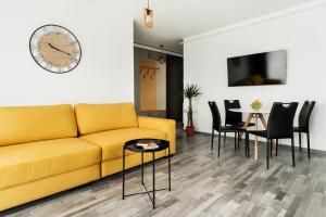 een woonkamer met een gele bank en een tafel bij Skylark - Miami Studio with Terrace & Mountain View in Braşov