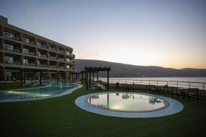 um hotel com duas piscinas em frente a um corpo de água em Atana Khasab Hotel em Khasab
