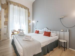 een slaapkamer met een groot bed met witte lakens en rode kussens bij Orma Design Rooms - Historic centre in Cagliari