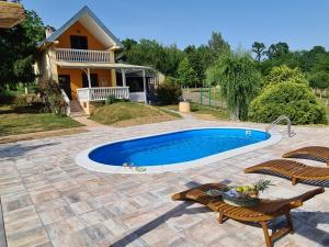 a swimming pool with two chairs and a house at Croatia Cottage in Nova Kapela