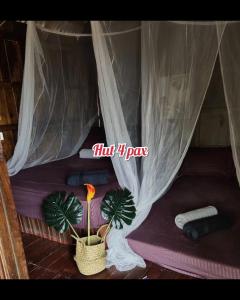 un letto con una tenda con due piante all'interno di Harrera Perhentian, Long Beach a Isole Perhentian