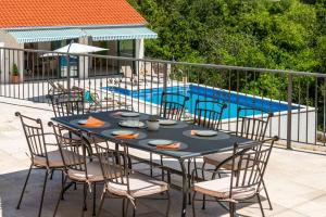 a table and chairs sitting next to a swimming pool at Villa Konavoski Miri in Gruda