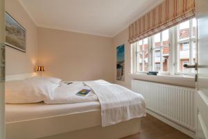 a white bedroom with a bed and a window at Ferienwohnung Seeschwalbe in Südstrand