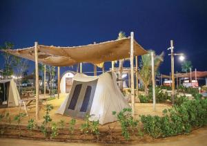 a tent and a slide in a park at night at Bab Al Nojoum Hudayriyat Camp in Abu Dhabi