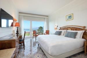 um quarto com uma cama, uma secretária e uma janela em Grand Hotel de la Ville em Sorrento