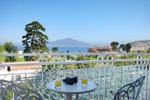 a table on a balcony with a view of the water at Grand Hotel de la Ville in Sorrento