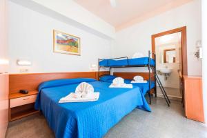 een slaapkamer met een blauw bed en handdoeken bij Hotel Pacific in Rimini