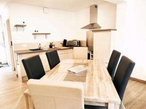 a dining room table with chairs and a kitchen at ⁂⁂ LE GRAND DUC Appartement [CLEDICIHOME] / Magnifique vue sur les montagnes / 4 KMs DE GERARDMER ! ⁂⁂ in Rochesson