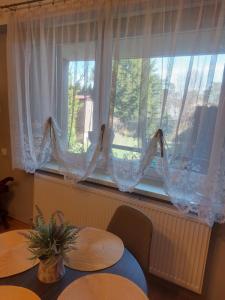 dos mesas delante de una ventana con cortinas en Zakątek na Krzywej, en Mrągowo